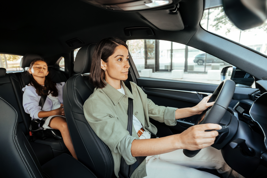 Mujer conduciendo coche con su hijo menor durmiendo en el asiento trasero