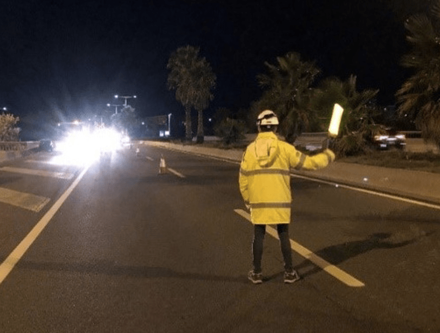 Vehículos circulando junto a operarios y señalización en un tramo de carretera en obras