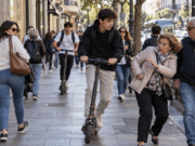 El 1 de octubre cambia el Reglamento, pero ¿quién hará cumplir las nuevas normas en la ciudad? Patinetes eléctricos circulando por una acera entre peatones en un entorno urbano, ejemplo de conflicto de convivencia y seguridad vial en la ciudad.