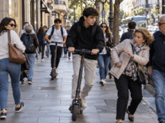 Patinetes eléctricos circulando por una acera entre peatones en un entorno urbano, ejemplo de conflicto de convivencia y seguridad vial en la ciudad.